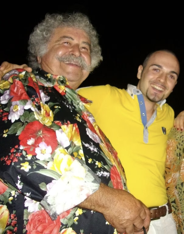El artista Edouard Tateossian, con camisa de flores, abraza a Davide Cristofaro en la cena