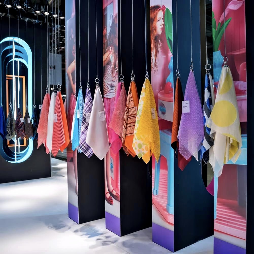 Les tissus du Japan Observatory à Milano Unica 2019, suspendus en rang devant des panneaux colorés : rayures, carreaux, pois et transparences