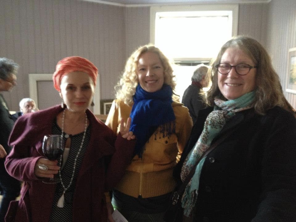Tre visitatrici sorridenti, una con un calice di vino, alla S9 Galleri