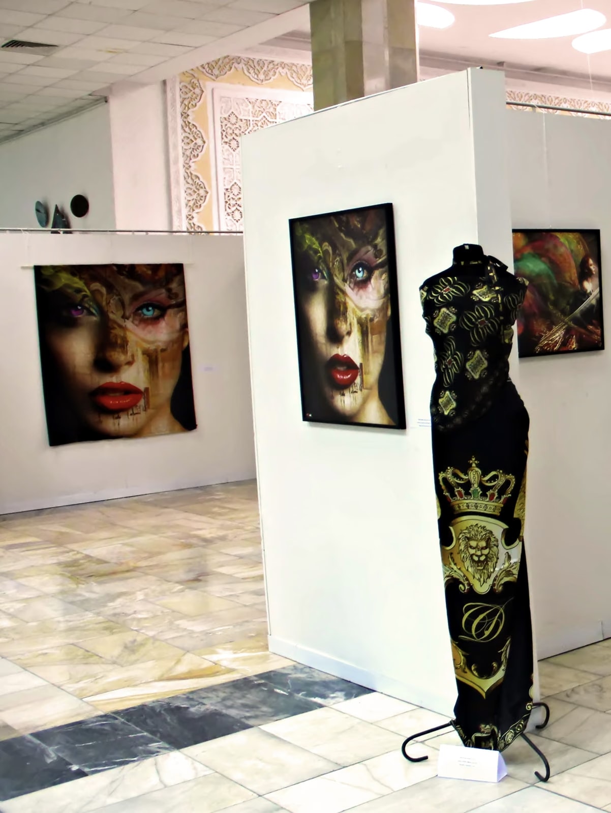 Davide Cristofaro’s black and gold silk dress on a mannequin, among the white walls of the exhibition