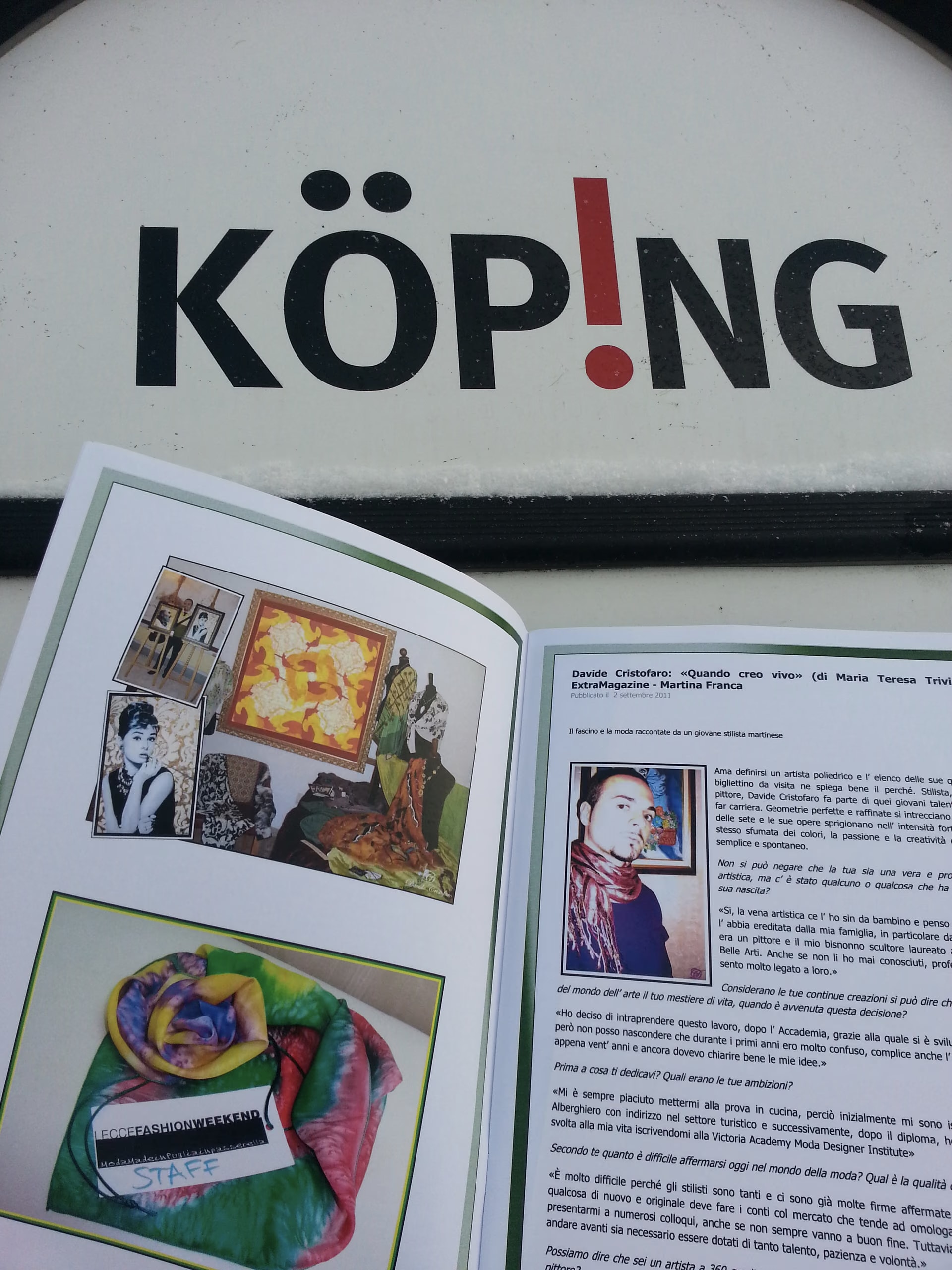 Der Kunst- und Modekatalog von Davide Cristofaro, aufgeschlagen vor dem Schild von Köping, auf der Seite des Interviews im ExtraMagazine