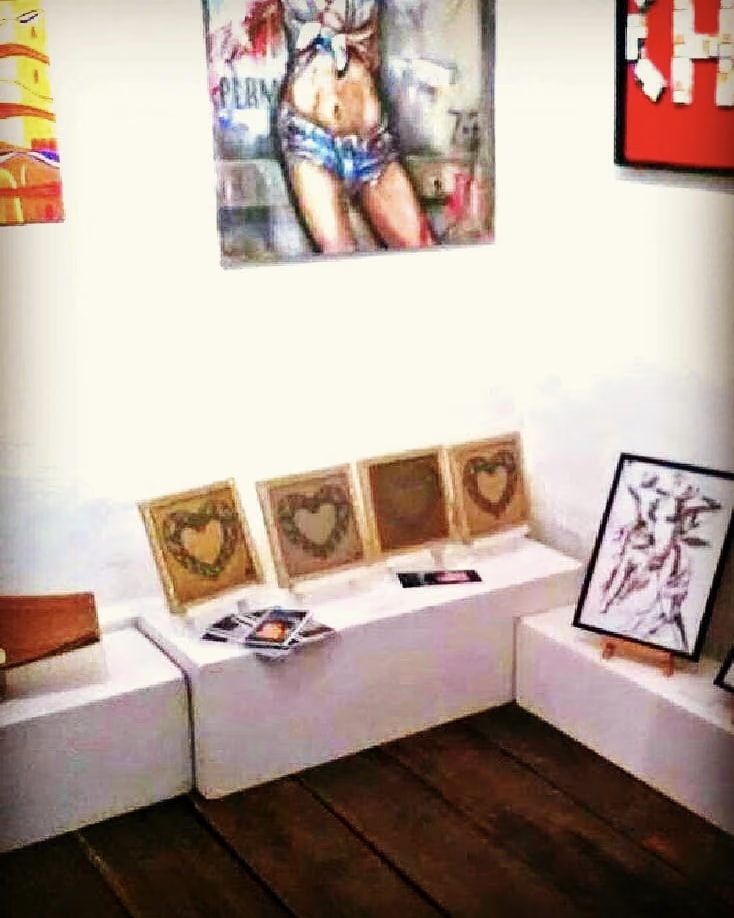 Die vier Leinwände von Düsteres Herz in einer Reihe auf einem weißen Sockel der Galleri T, neben den Karten von Davide Cristofaro