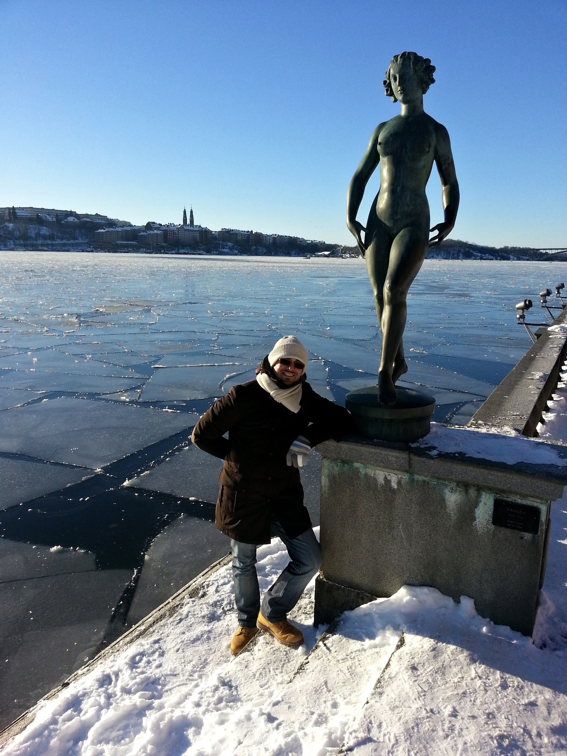 Davide Cristofaro neben der Statue „Dansen“ von Carl Eldh am Ufer vor dem Stockholmer Rathaus, hinter ihm das gefrorene Wasser