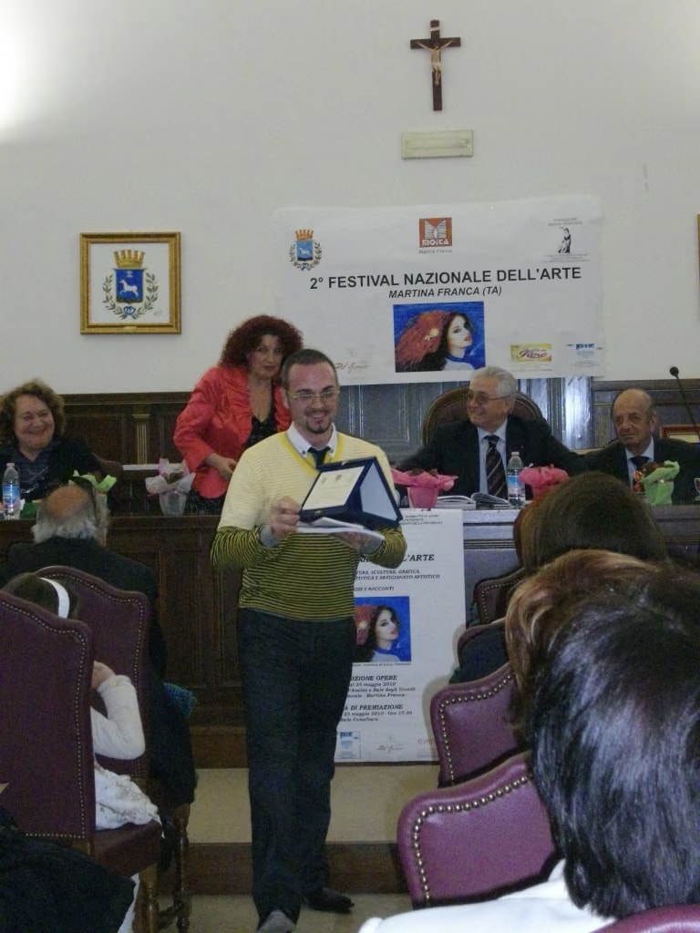 Davide Cristofaro con el primer premio de la sección de técnica mixta innovadora, ante la mesa del jurado