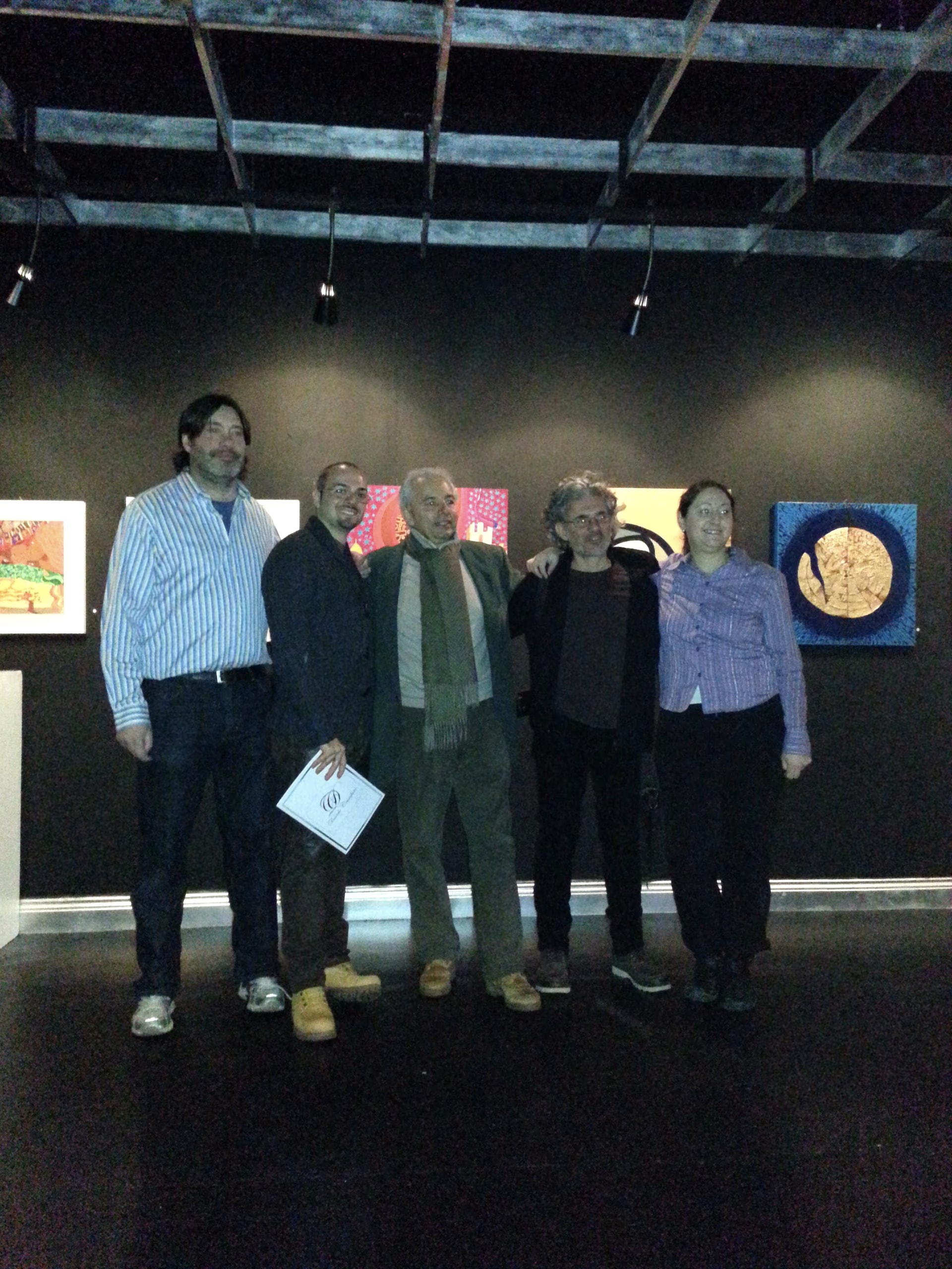 Davide Cristofaro mit den Galeristen Riccardo Baldelli und Elisa Bastiani und zwei Künstlern im schwarzen Raum der Galleri Quirinus