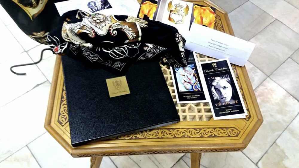 The carved wooden table with Davide Cristofaro silk scarves, their black box with the gold plaque, leaflets and the Fashion catalogue