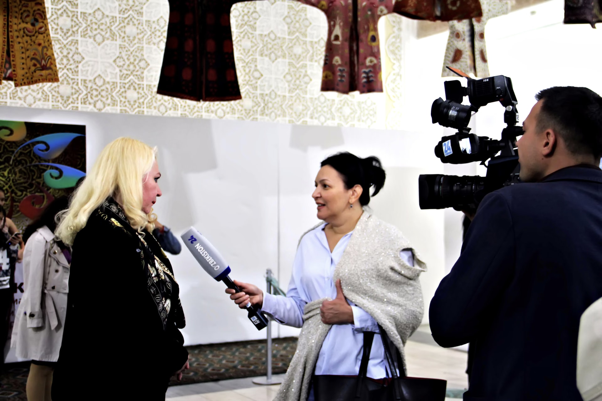 Aida Abdullaeva wearing Davide Cristofaro’s scarf, interviewed by Uzbekistan 24 in front of the camera