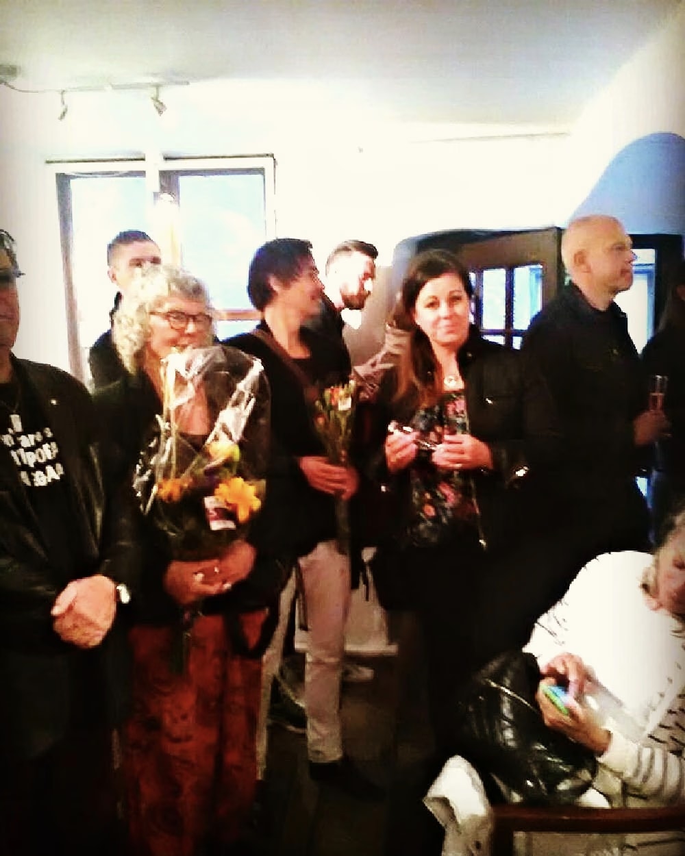 Besucher im Raum der Galleri T mit Blumen und Gläsern während „In the Depth of Colours“