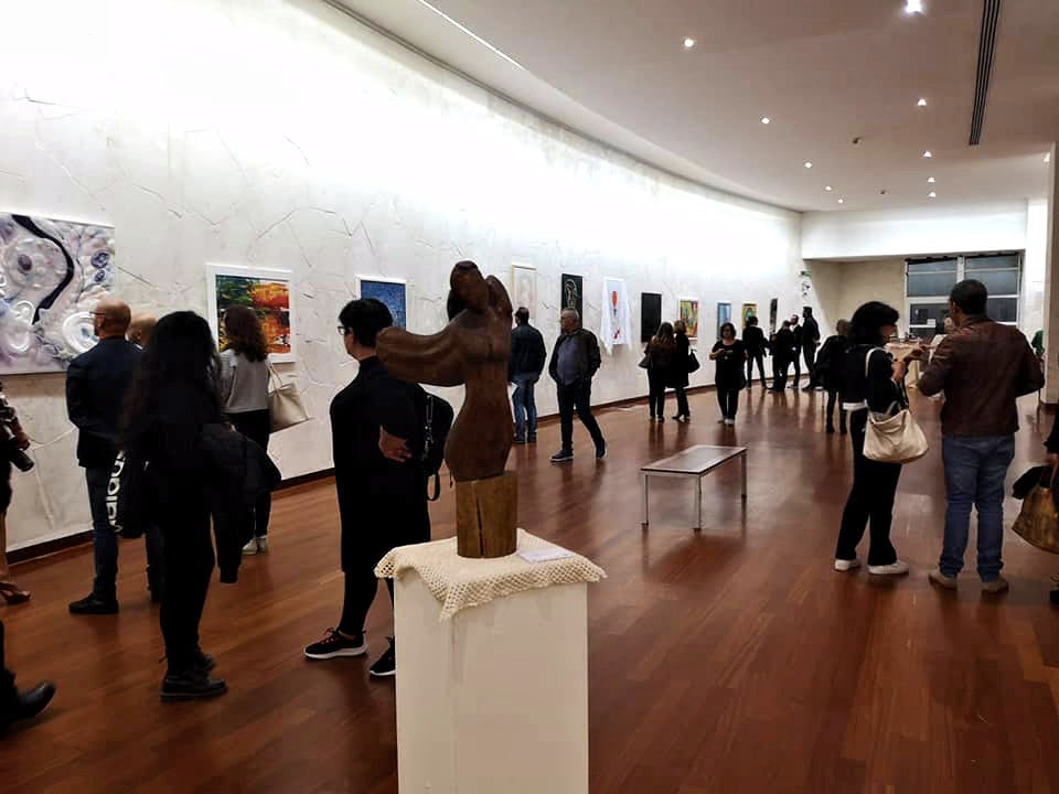 La grande salle du Museo Michetti pendant le vernissage, avec les tableaux le long du mur courbe et une sculpture au centre