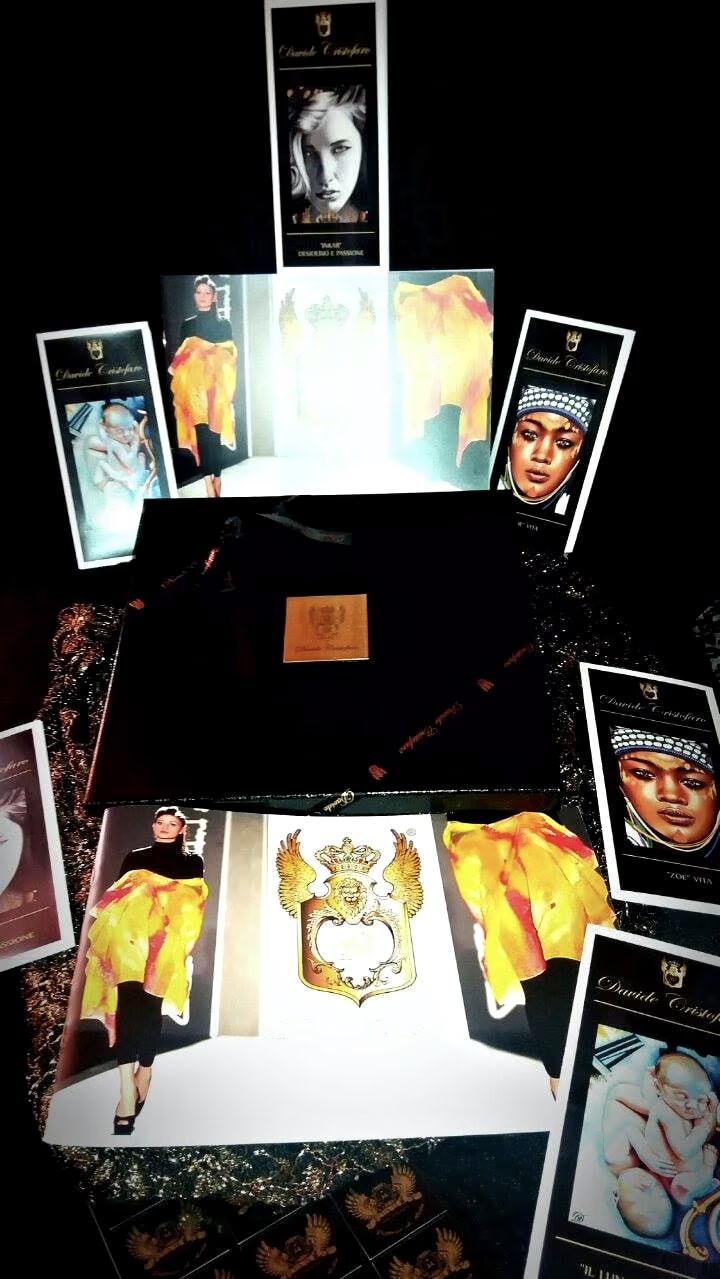 The black box of a Davide Cristofaro scarf, with its gold plaque, among the leaflets and the Fashion catalogue