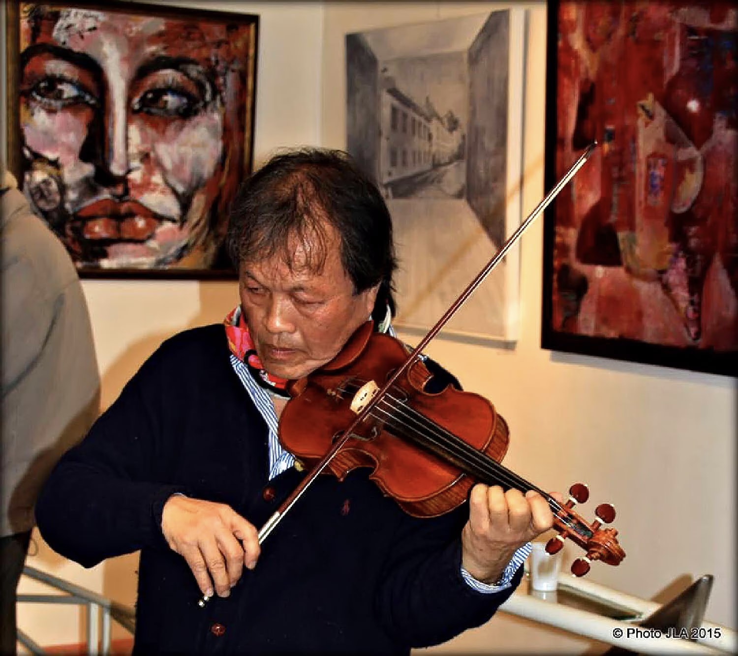 A violinist plays among the paintings during the “Paris 2015” opening at the Galerie Thuillier