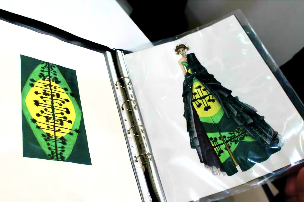 Raccoglitore aperto con il disegno di un motivo di palme verde e giallo e il bozzetto di un abito lungo verde e nero