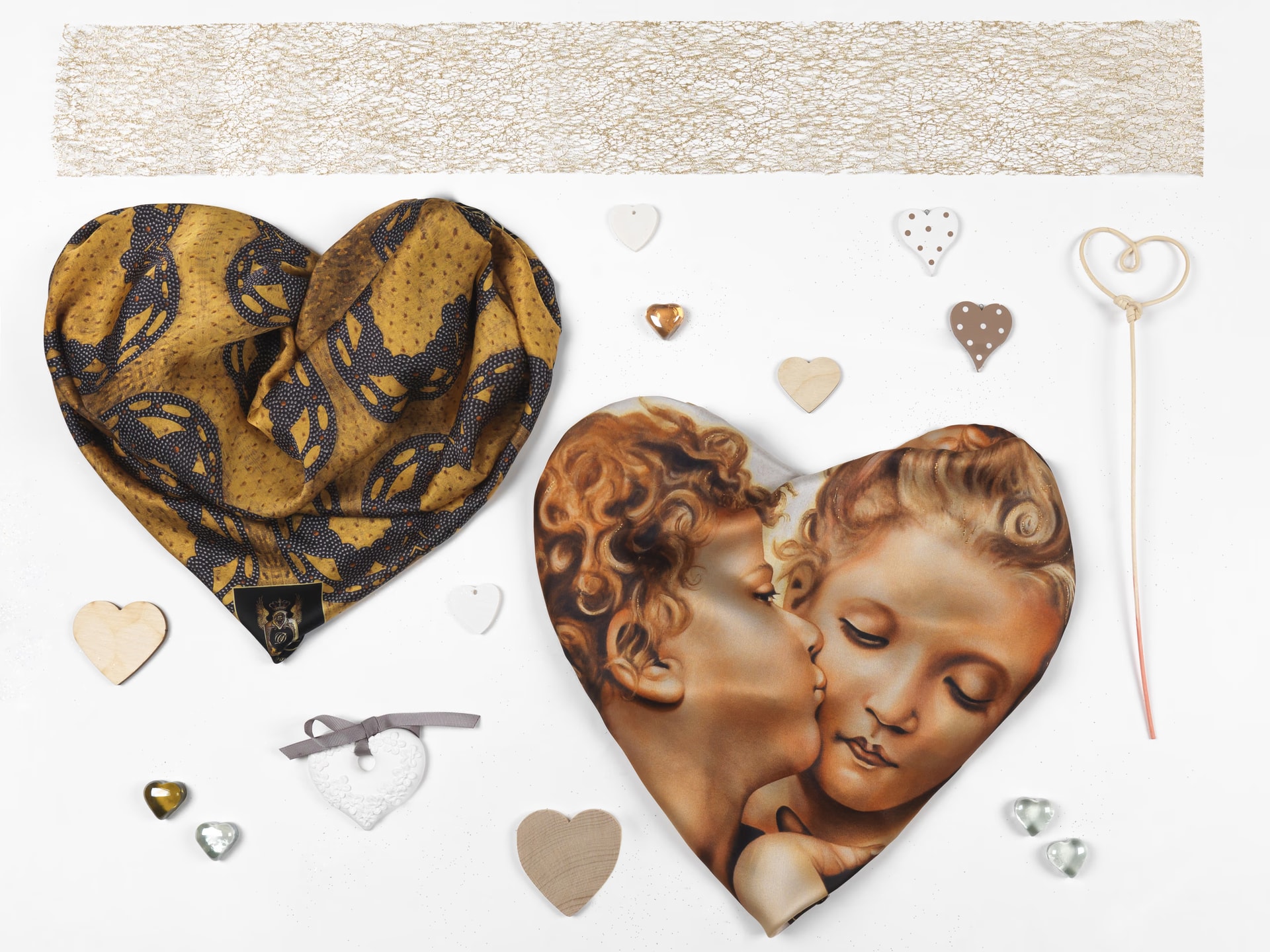 Due foulard piegati a forma di cuore, uno oro e blu e l’altro con i due angeli che si baciano di The First Kiss, fra piccoli cuori decorativi