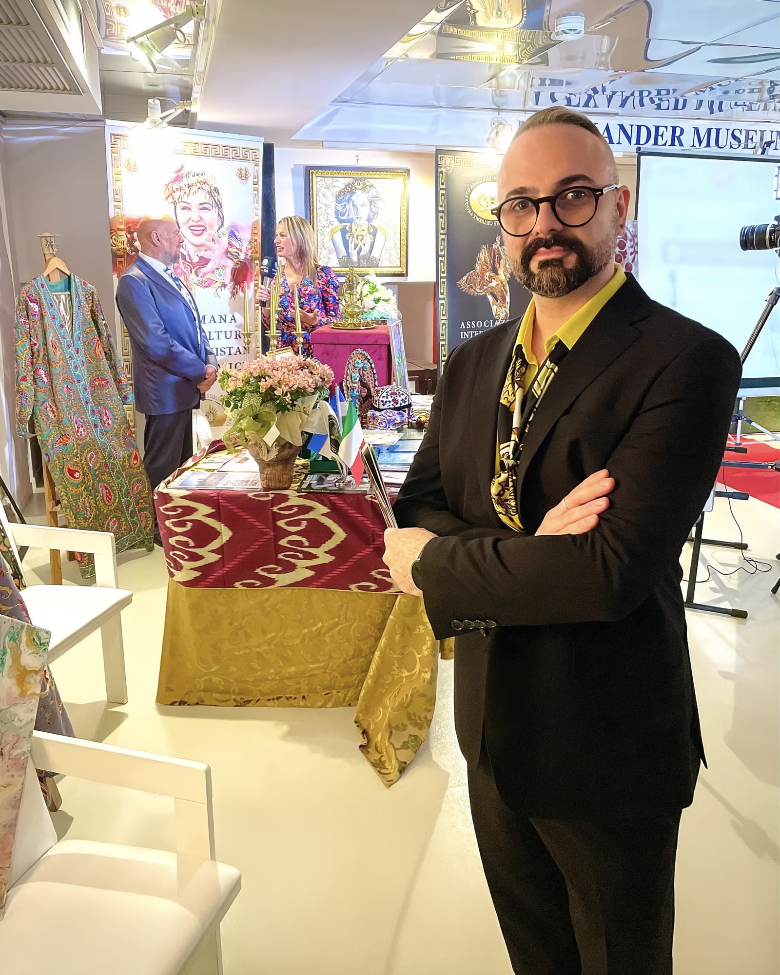 Davide Cristofaro im Saal der Woche der usbekischen Kultur, zwischen traditionellen Gewändern, Stoffen und Flaggen
