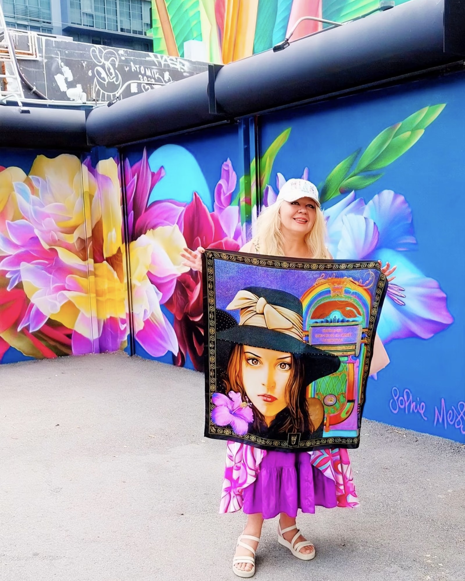 Aida Abdullaeva con il foulard Fanny davanti a un murale di grandi fiori a New York