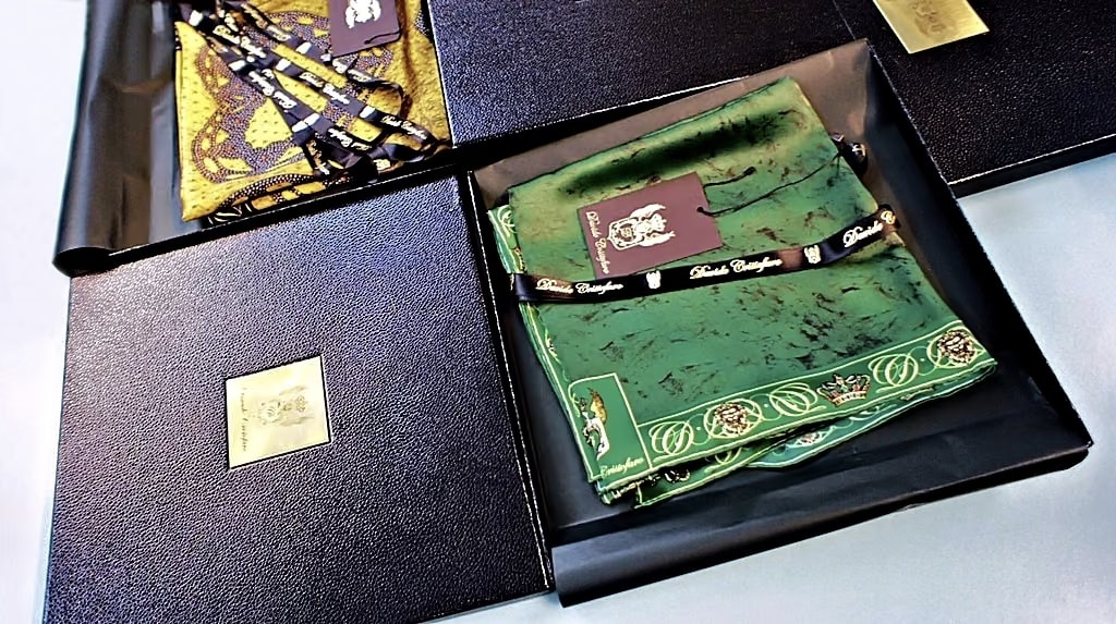 Foulard di seta Davide Cristofaro nelle scatole regalo nere, uno verde con bordo a medaglioni e uno giallo e nero, con nastro e cartellino della maison