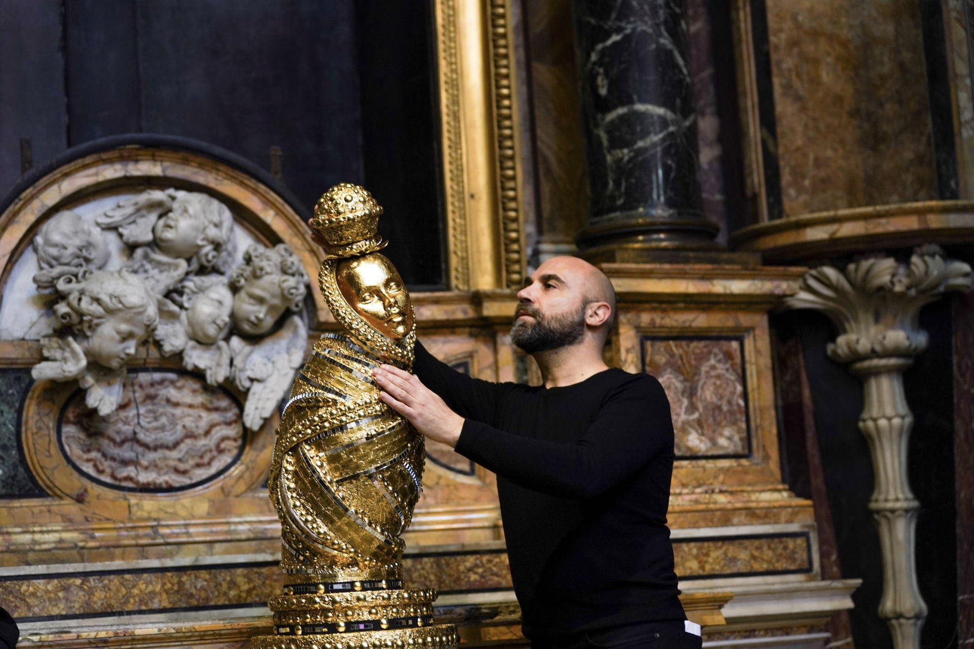 Giuseppe Fata accanto alla sua scultura «Mother», con la mano sul manto dorato, nella Basilica di Santa Maria in Montesanto