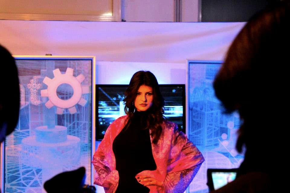 Modella in nero con un foulard di seta rosa e viola sulle spalle, in studio davanti allo schermo
