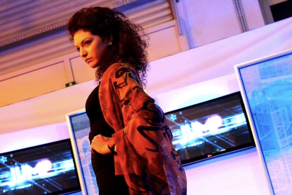 Modella dai capelli ricci con una seta nei toni del bruciato e decori neri sulle spalle