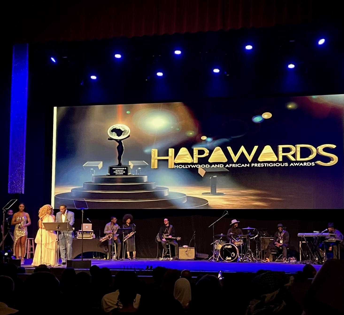 Il palco degli HAPAwards 2023 all’Alex Theatre con il logo sul grande schermo e i musicisti sotto le luci