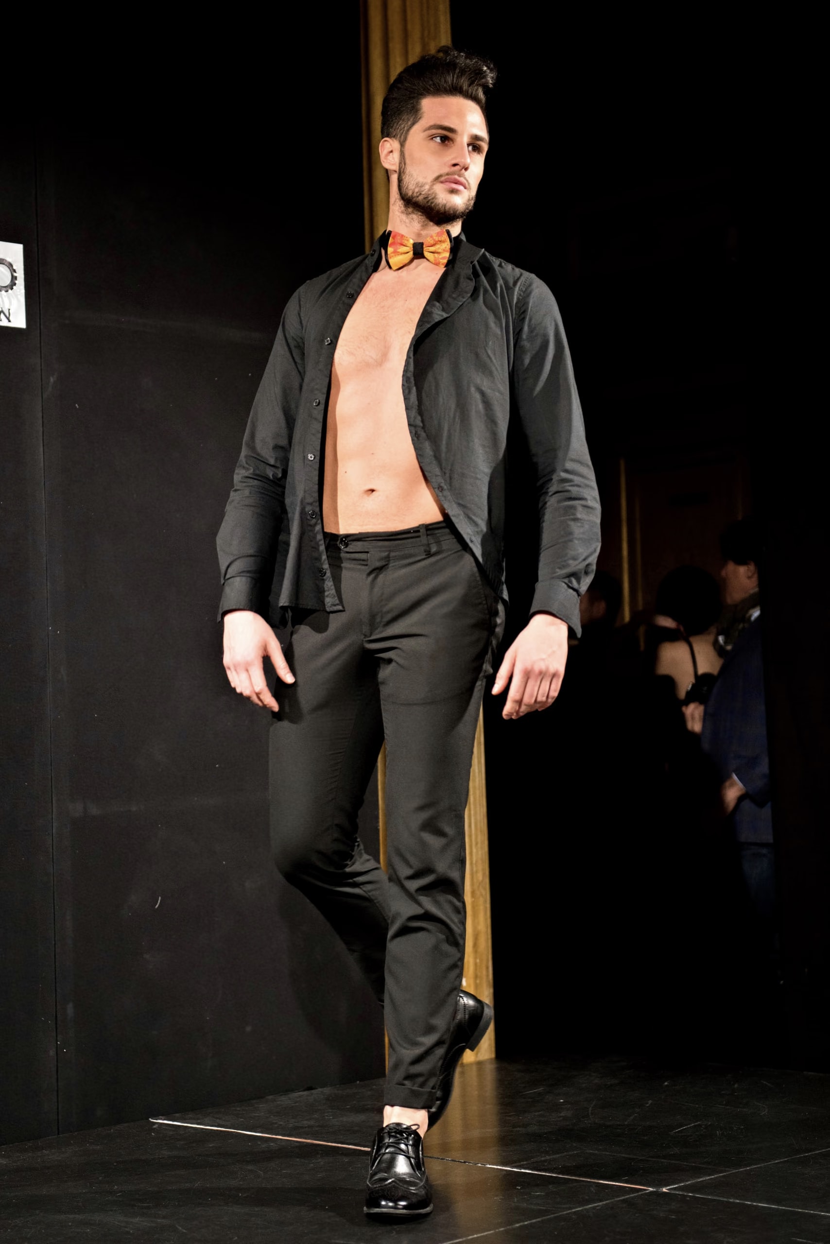 Model in offenem schwarzem Hemd und Fliege von Davide Cristofaro auf dem Laufsteg