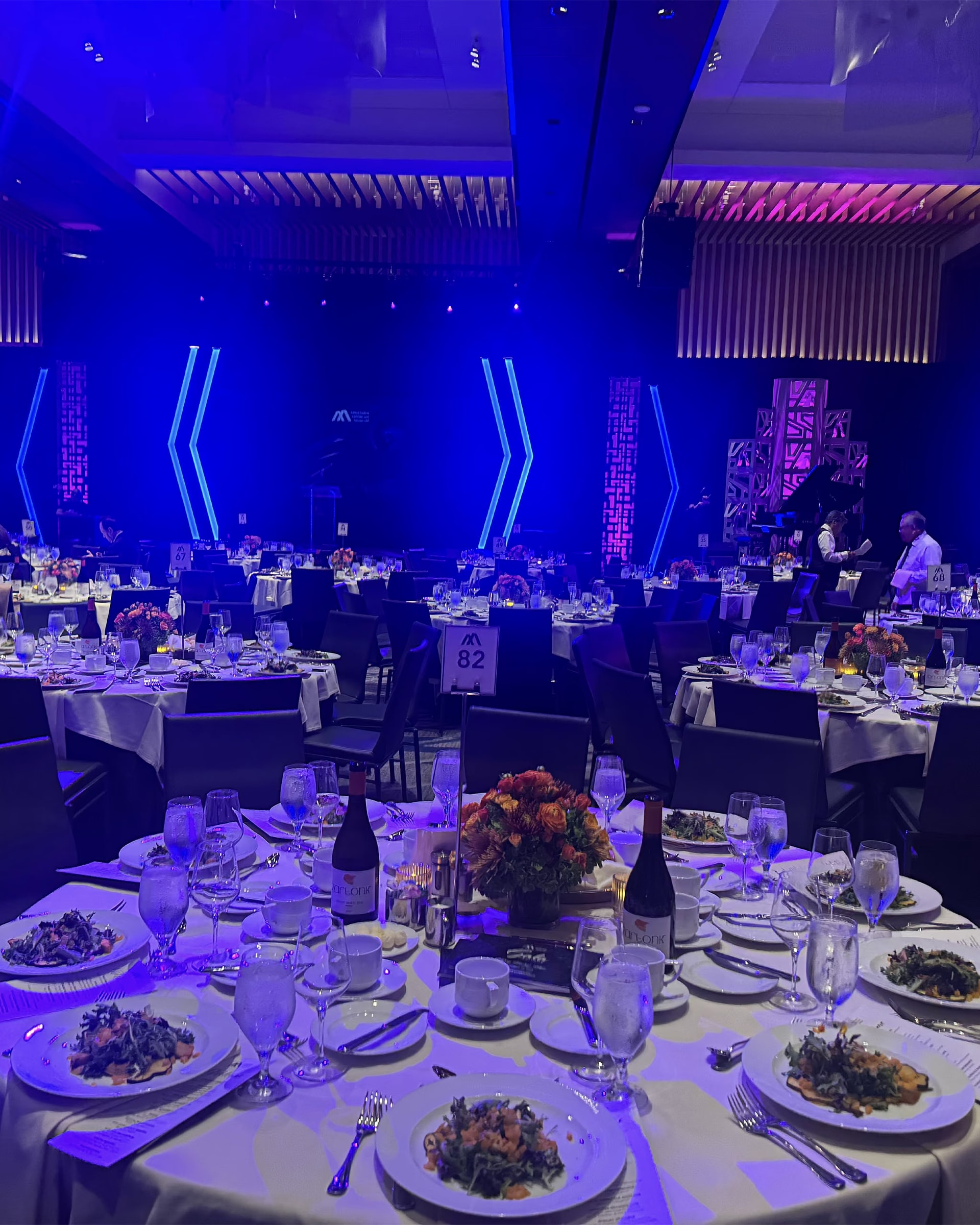 The ballroom of the Heritage Gala 2025 at the InterContinental Los Angeles, with the tables set and blue lights