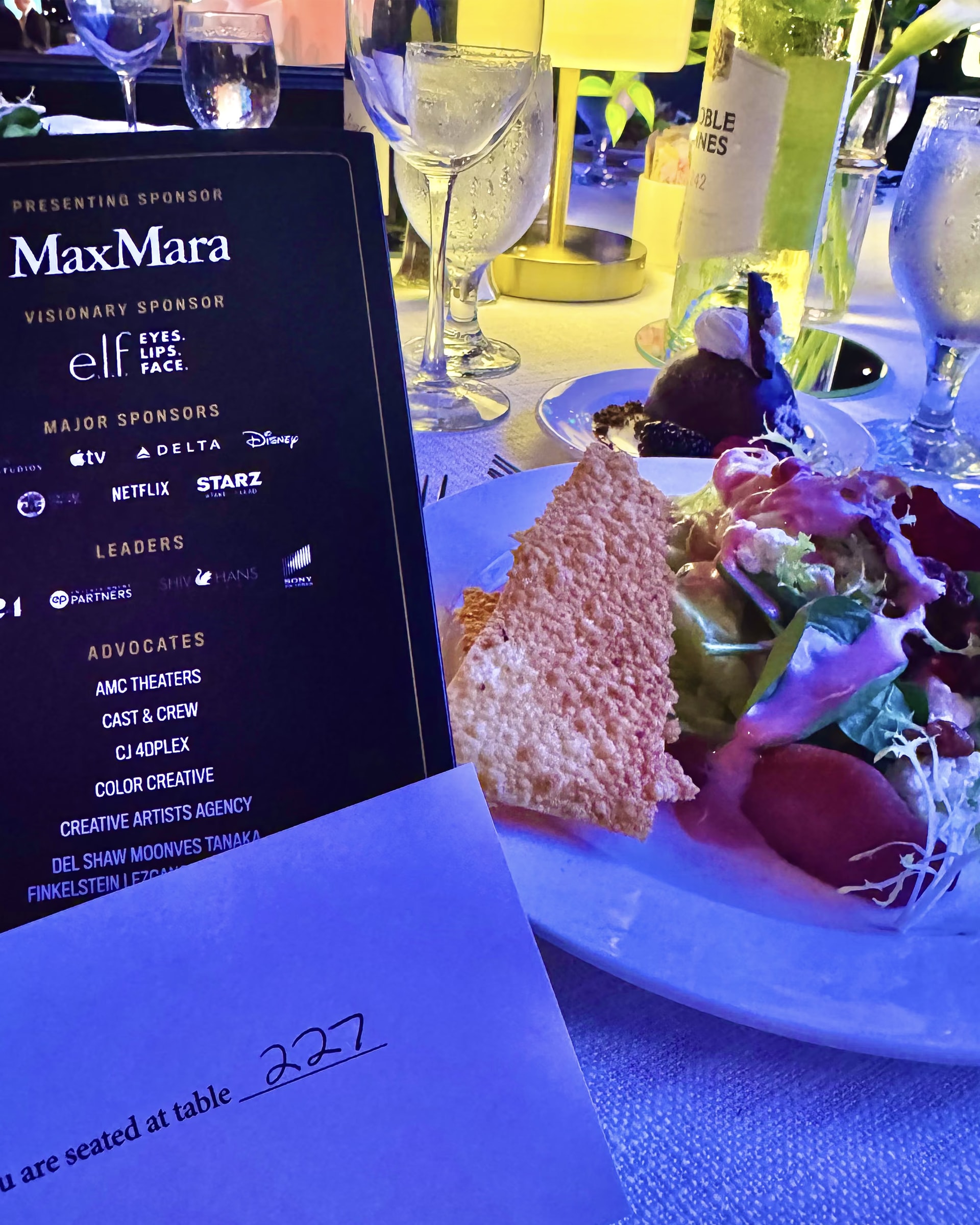Il biglietto con gli sponsor della serata, fra cui Max Mara, e il segnaposto del tavolo 227 accanto a un’insalata