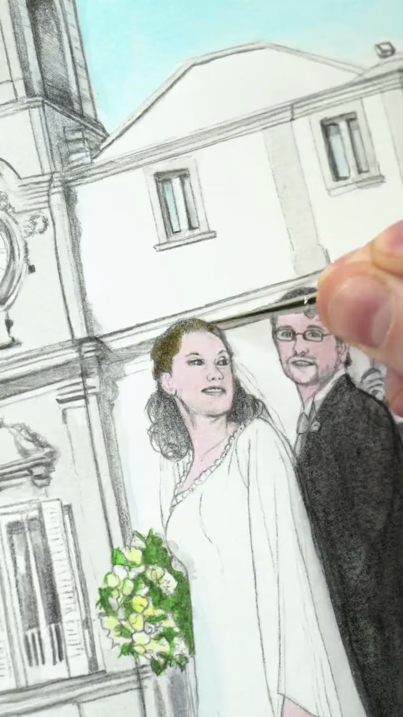 I volti degli sposi colorati sotto la lente, con il pennello sottile sul disegno a matita