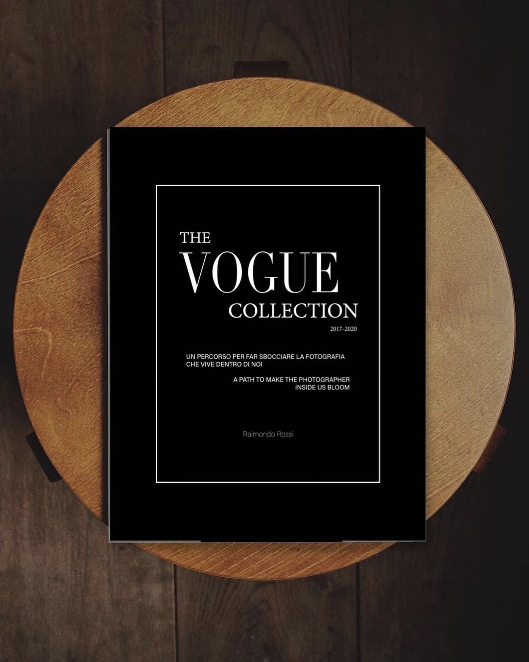 Copertina nera del libro The Vogue Collection 2017-2020 di Raimondo Rossi, appoggiato su uno sgabello di legno rotondo